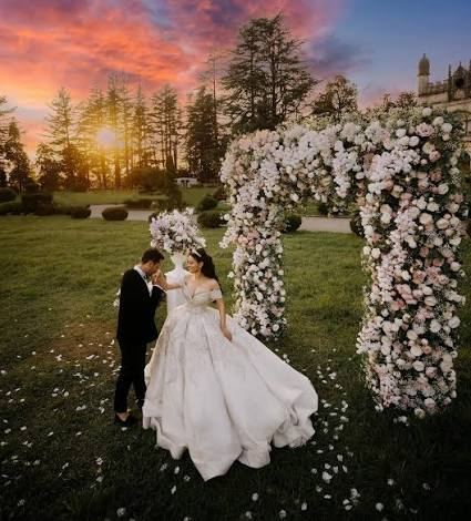Couple kissing under a floral arch at sunset